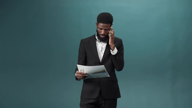A man in a black tuxedo talks on the phone and has some questions about important documents