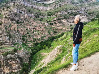 A girl on the background of a view of the ancient village of Kahib in the evening in the mountains of Dagestan. Russia