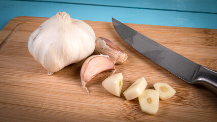 Knife and cut garlic on a bamboo wooden cutting board