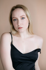 Fototapeta premium Graceful young woman posing against beige wall.