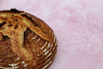 A high angle view of a crusty loaf of bread against a pink background