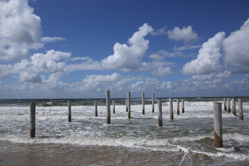 Wooden poles at the Dutch coast standing in the water due to high tide
