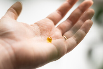 Close up of hand full of yellow softballs. Taking supplements, vitamin D or omega. Wellbeing biohacking concept