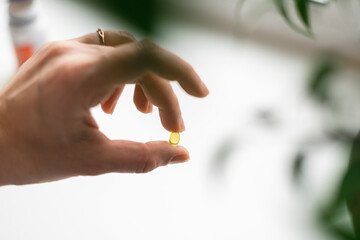 Close up of hand full of yellow softballs. Taking supplements, vitamin D or omega. Wellbeing biohacking concept