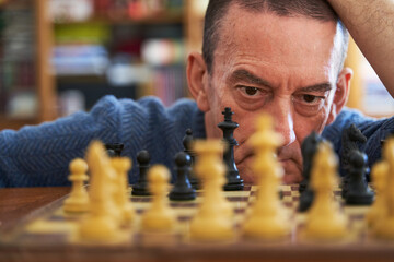 Memory loss prevention concept. Senior man looking at chess board