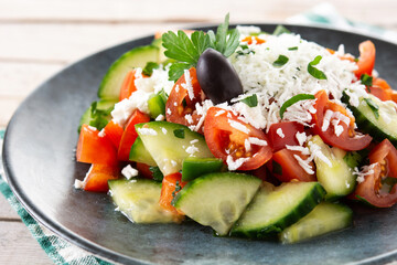 Traditional Bulgarian shopska salad with tomato,cucumber and bulgarian sirene cheese on wooden table