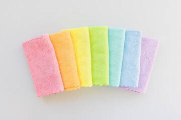 New folded microfiber cloth for cleaning in seven rainbow colors on gray background. Cleaning micro fabric towels for dusting and polishing. Domestic household cleaning service concept. Top view, copy