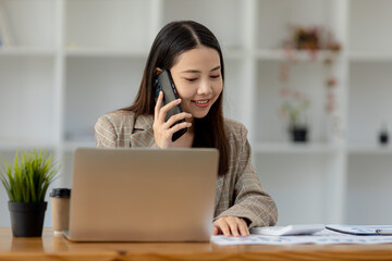 Asian woman talking on the phone, she is a salesperson in a startup company, she is calling customers to sell products and promotions. Concept of selling products through telephone channels.