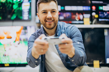 Man with joy stick playing virtual games at store