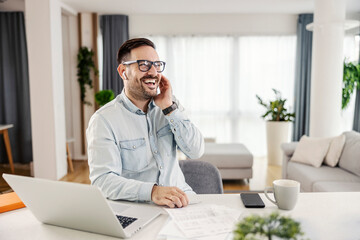 Obraz premium A happy man sitting at his cozy home and using technologies.