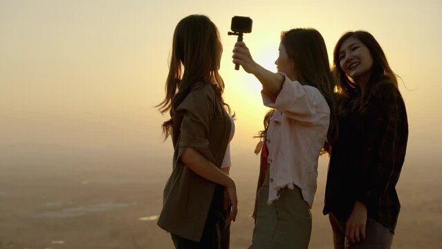 girl friend group Asians blogger standing and caper enjoying the beauty of nature in the evening sunset and shoot video from their action cams to show off to their friends in social media,freedom conc