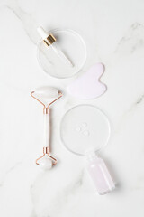 Pink liquid gel or hyaluronic serum in petri medical dish with pipette. Gua sha set tools for massageing. Hydrating and skin care concept