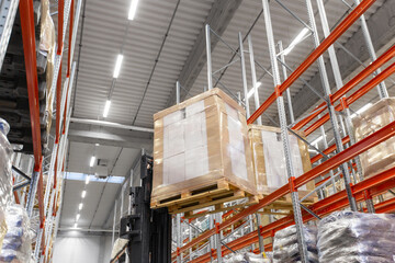 logistic, storage, shipment and industry concept - forklift loader loading cargo to warehouse shelves