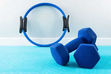 Dumbbells and a ring for sports on a blue mat.