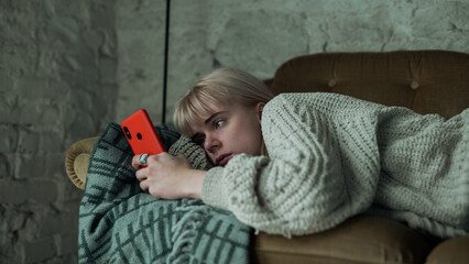 Depressed Young Blonde Woman Scrolling Through Her Phone, Refusing to Get Up From the Sofa....