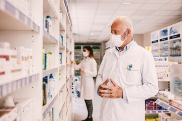 Fototapeta premium An old pharmacy worker looking at shelves with medicines in a pharmacy.