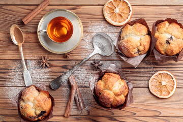 Top view of four homemade delicious muffins with spoons and cinnamon on wooden background.