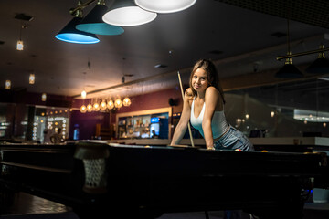 female player playing pool and aiming the billiard ball with cue