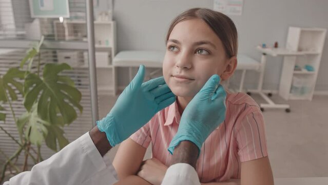Handheld POV slowmo shot of 13-year-old Caucasian girl having her lymph nodes examined by male pediatrician during appointment in clinic