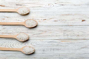 salt on many wooden spoon on wood background. Spoons with different salt