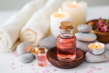 Fototapeta na wymiar Concept of spa treatment in salon. Natural organic oil, towel, candles as decor. Atmosphere of relax, serenity and pleasure. Anti-stress and detox procedure. Luxury lifestyle. White wooden background