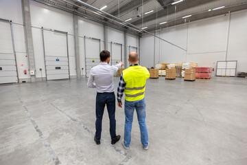 logistic business and people concept - businessman showing warehouse to worker