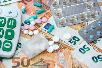 pills with calculator on pile of Euro money as background