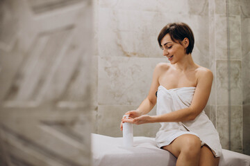 Woman pressing on dispenser and squeezing moisturizing cream