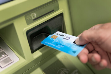 Hand of a man with a credit card, using an ATM. Man using an atm machine with his credit card.