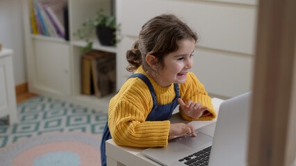 Smiling caucasian girl playing on computer game, happy kid using computer for online class, home education concept