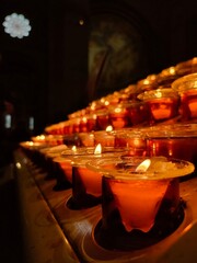 Candles in a church. Candles flame close up. Bright in the dark. Canldes lights. Calm. Paris, France