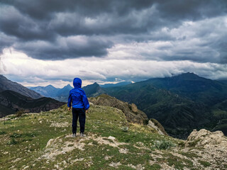 Naklejka premium A boy on the background of a breathtaking view of the mountains during a thunderstorm in Dagestan, Caucasus, Russia