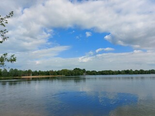 Eine Spiegelung des Himmels im Wasser des Sees. Der Himmel mit Wolken spiegelt sich im Wasser des Ozeans. Das Himmelblau macht das Meer schön blau. Die Wasseroberfläche ist ruhig. Reflexion. 