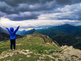 A boy on the background of a breathtaking view of the mountains during a thunderstorm in Dagestan, Caucasus, Russia