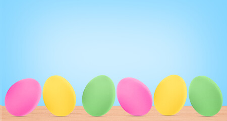 Colorful Easter eggs on a wooden table on a blue background.