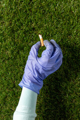 environment, volunteering and ecology concept - close up of hand in glove picking cigarette butt...