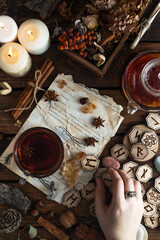 Wooden runes are lying on the table among the papers with notes. There is a mug of tea next to it. Astrology and esotericism.