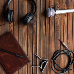 Music theme. Headphones, notepad, jack and capo on a wooden background. 