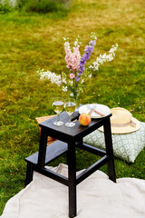 leisure and drinks concept - close up of picnic basket, flowers and glasses of champagne on wooden...