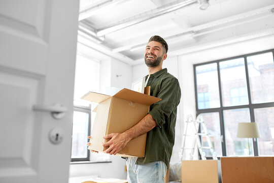 Moving, People And Real Estate Concept - Happy Smiling Man Holding Box With Stuff At New Home