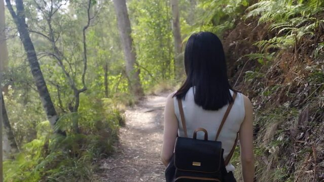Young Asian woman walking in nature and looking back