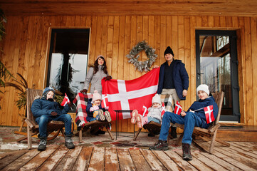 Family with Denmark flags near they wooden house. Travel to Scandinavian countries. Happiest danish people's .