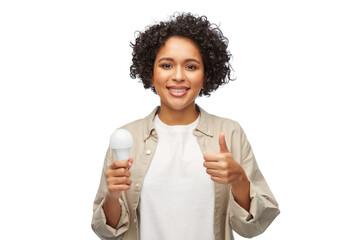 eco living, energy saving and sustainability concept - portrait of happy smiling woman holding lighting bulb over white background