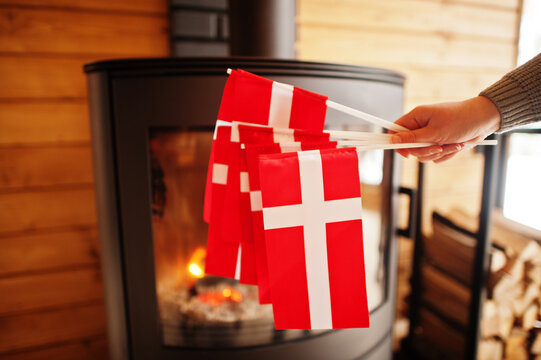 Woman hold Denmark flags against fireplace. Travel to Scandinavian countries. Happiest danish people's .