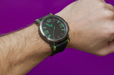 black watch with a green dial on a male hairy hand