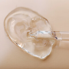 Transparent gel hyaluron serum in pipette on beige skin tone shade color background. Water Texture gel surface of cosmetic skin health product Sample swatch of chemical gel in lab. Square Close up