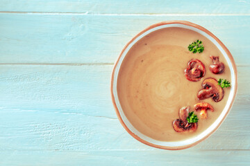 Mushroom soup, garnished with parsley, shot from the top on a teal wooden background with a place for text