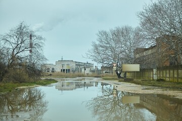 Obraz premium An old abandoned industrial area. Factory buildings or factories. Puddles and road signs.