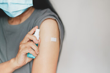 senior hand holding spray alcohol bottle, wearing medical face mask after vaccinated or inoculation  booster dose  due to spread of corona virus, population, social or herd immunity concept