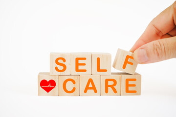 self-care word and red heart with heartbeat on wooden blocks with hand holding f alphabet cube for...